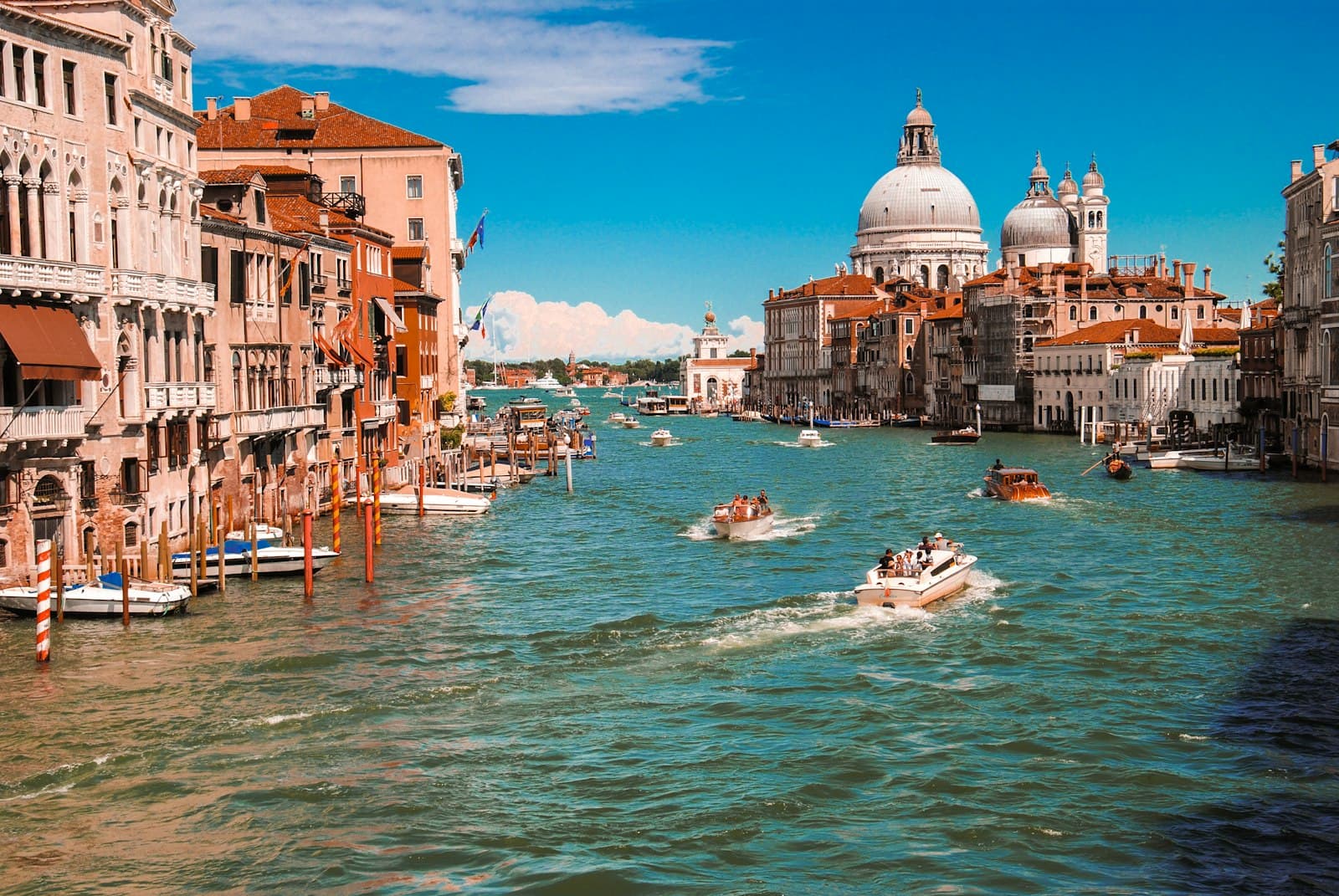 Boats on Venice’s Grand Canal between colorful waterfront buildings and a domed church